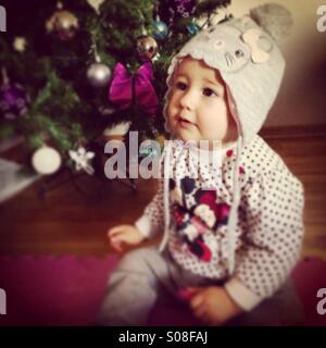 Kleines Babymädchen sitzen in der Nähe von Weihnachtsbaum Stockfoto