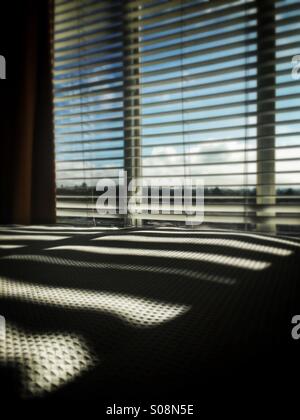 Fenster-Venetian blinds Schattenwurf auf Bett Stockfoto