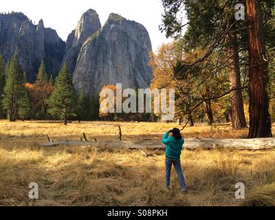 Eine Frau nimmt Bilder der Kathedrale Felsen im Herbst. Yosemite Valley, Yosemite-Nationalpark, Mariposa County, Kalifornien, USA Stockfoto