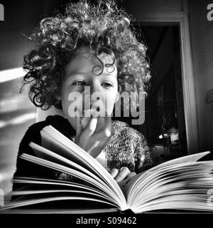 Mädchen einen Apfel essen, beim Lesen eines Buches. Stockfoto