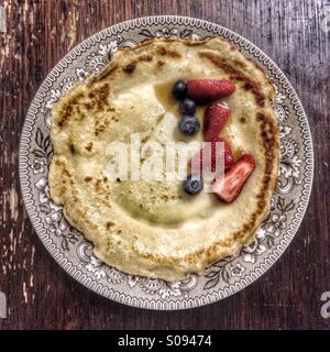 Crepe (französische Pfannkuchen) mit Erdbeeren, Blaubeeren und Ahornsirup. Stockfoto