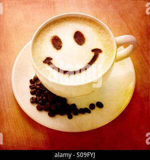 Eine wärmende Tasse heißen Kaffee mit einem Schokoladenpulver Smiley Stockfoto