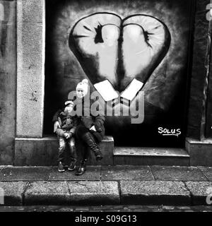 Mama & junge sitzen vor Graffiti in Dublin Stockfoto