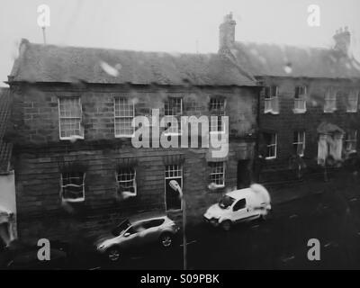 Miserable britische Wetter - Starkregen in einem Fenster mit Blick auf eine Wohnstraße in Northumberland, England. Stockfoto