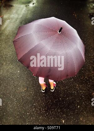Kind unter einem Regenschirm Stockfoto