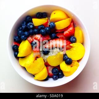 Sommerliche Haferflocken bedeckt mit bunten Früchten und Beeren Stockfoto