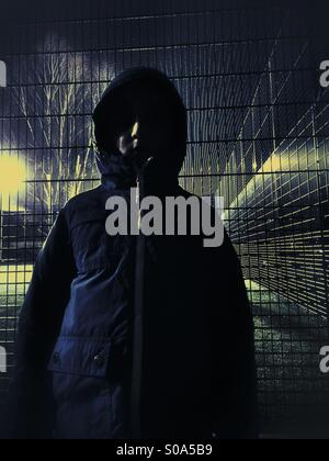 Junge im Regenmantel im Freien bei Nacht Stockfoto