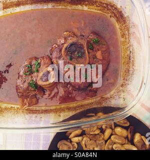 Osso Buco Mahlzeit in Kasserolle mit in Scheiben geschnittenen Champignons Stockfoto