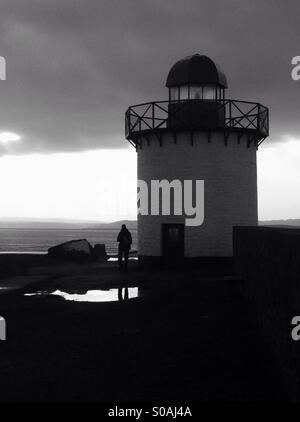 Schwarz / weiß Silhouette des Mannes neben Burry Port Leuchtturm Stockfoto