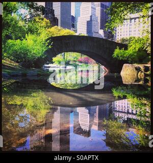 Ansicht der Gapstow-Brücke im Central Park mit Gebäuden reflektiert im Teich. Stockfoto