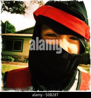 Sechs Jahre alter Junge lächelnd in seinem Ninja Halloween-Kostüm. Stockfoto