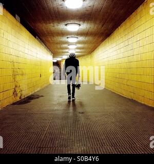Junger Mann zu Fuß unter einem gelben tunnel Stockfoto