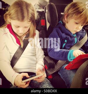Kinder spielen auf Bildschirmen in einem Auto Stockfoto