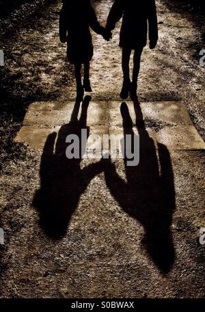 Zwei junge Mädchen hand in hand gehen und wirft lange Schatten Stockfoto