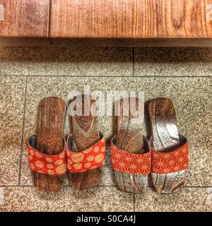 Zwei Paare von japanische Holzsandalen mit orange geometrische Stoffmuster. Stockfoto