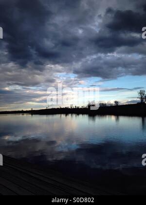 Dunkle Wolken schweben über einem ruhigen See (2). Stockfoto