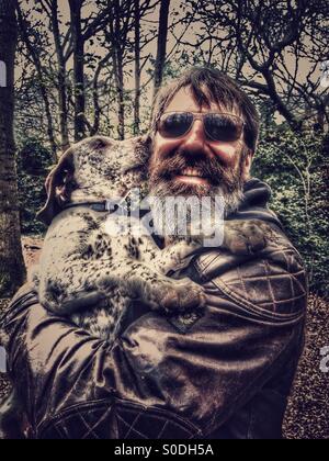 Mann, der seine Welpen auf einem Spaziergang im Wald Stockfoto