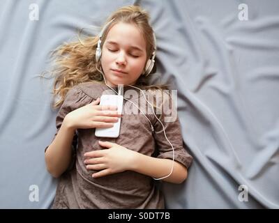 Es klingt wie ein Traum. Junges Mädchen auf dem Bett liegen und träumen von etwas mit geschlossenen Augen. Stockfoto