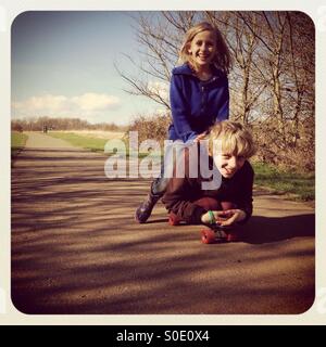 Bruder und Schwester auf skateboard Stockfoto