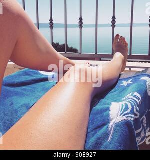 Frau, Sonnenbaden am Balkon mit Blick aufs Meer Stockfoto