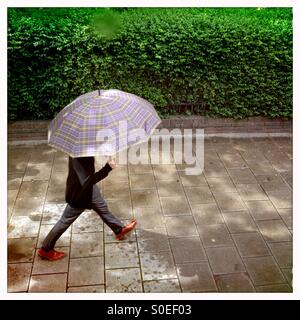 Elegant gekleidete Mann hält einen großen Regenschirm auf der Straße in London Uk Stockfoto