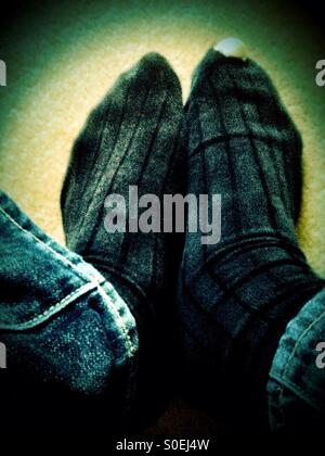 Ein altes Paar schwarze Socken mit einem Loch in eines der großen Zehen. Stockfoto