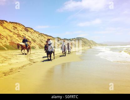 Reiter auf Pferden Richtung Norden eine endlose Länge der Breite California Beach an einem sonnigen Tag im Frühsommer. Stockfoto