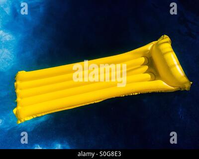 Gelbe aufblasbare Matte auf dunklen blauen Wasser schwimmen. Stockfoto