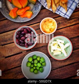 Oliven, Hummus, Käse und Melone auf einem Holztisch Stockfoto