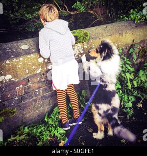 Ein Junge und sein Hund auf der Suche über eine Brücke. Stockfoto