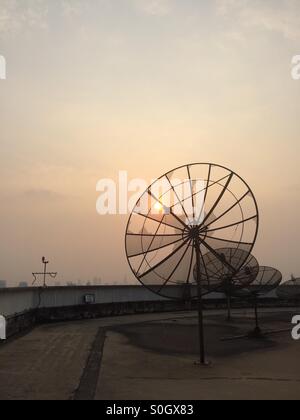 Schwarzen Kommunikation Satellitenschüsseln auf einem Gebäudedach bei Sonnenuntergang, Bangkok, Thailand. Stockfoto