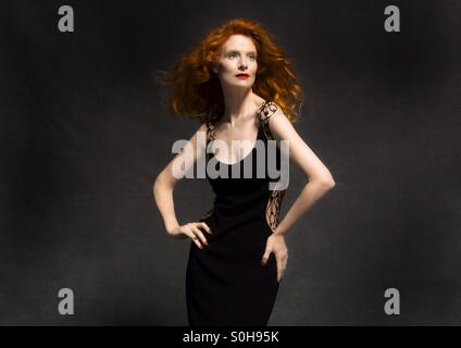 Rothaarige Model im schwarzen Kleid im studio Stockfoto
