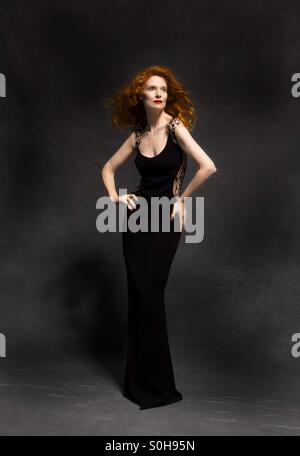 Rothaarige Model in langen schwarzen Kleid im studio Stockfoto