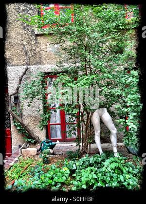 Baum mit menschlichen Schaufensterpuppe Beine in einem Garten in Greenwich Village sieht surreal. Stockfoto