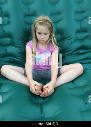 Nachdenklich Mädchen sitzt auf einer grünen Matratze Stockfoto