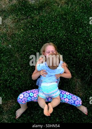 Mädchen liegend auf dem Rasen außerhalb mit ihrem Bruder Stockfoto