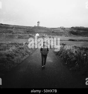 Eine Frau geht eine Straße hinunter. Doolin, co. Clare, Irland. Stockfoto