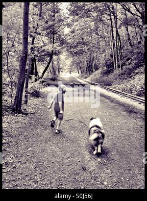 Junge und sein Hund einen Waldweg entlang. Stockfoto