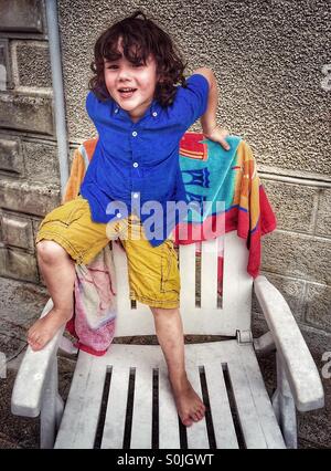 Vier Jahre alter Junge auf Terrasse Stuhl Stockfoto