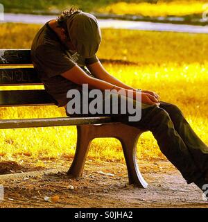 Mann schläft auf Bank Stockfoto