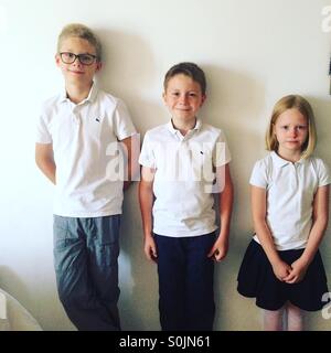 Drei Kinder, freuen sich Geschwister kurz vor ihrem ersten Tag der Schule-zwei jungen in schöne Outfits gekleidet ist zwar das jüngste Mädchen nicht. Stockfoto
