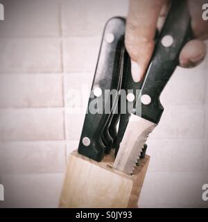 Hand zieht ein Steakmesser Stockfoto