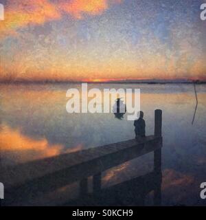 Kleiner Junge Sonnenuntergang von einem Dock. Stockfoto