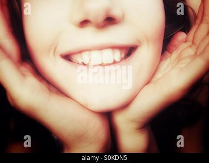 Nahaufnahme eines lächelnden Mädchens mit Gesicht in ihre Hände schalenförmig Stockfoto