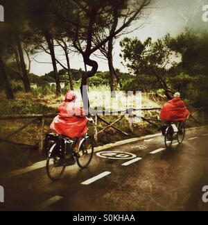 Ein paar mit roten Regenmäntel Radfahren im Regen Stockfoto