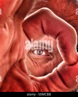 Mann auf der Suche durch Ordnung Zeichen gemacht durch seine Finger Stockfoto