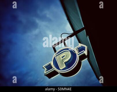 Weißen und blauen Neon Parkplatz Garage Zeichen gegen einen dunkelblauen bewölkten Himmel, am frühen Abend. Stockfoto