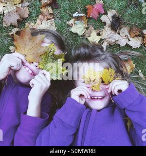 Schwestern, die das Spiel mit der Blätter im Herbst Stockfoto