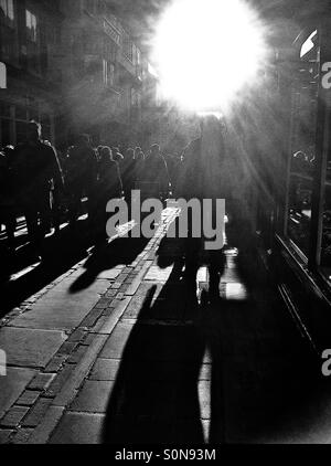 Silhouetten von Menschen entlang der gepflasterten Straße England UK Stockfoto