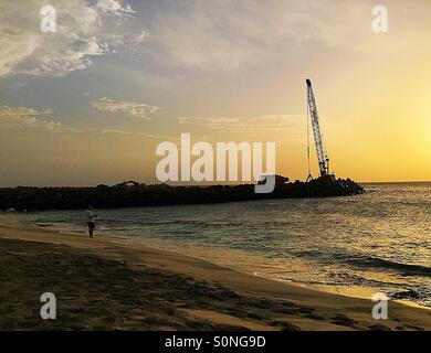 Mann Angeln bei Sonnenuntergang mit Kran auf einem Pier Sal Kapverden Stockfoto